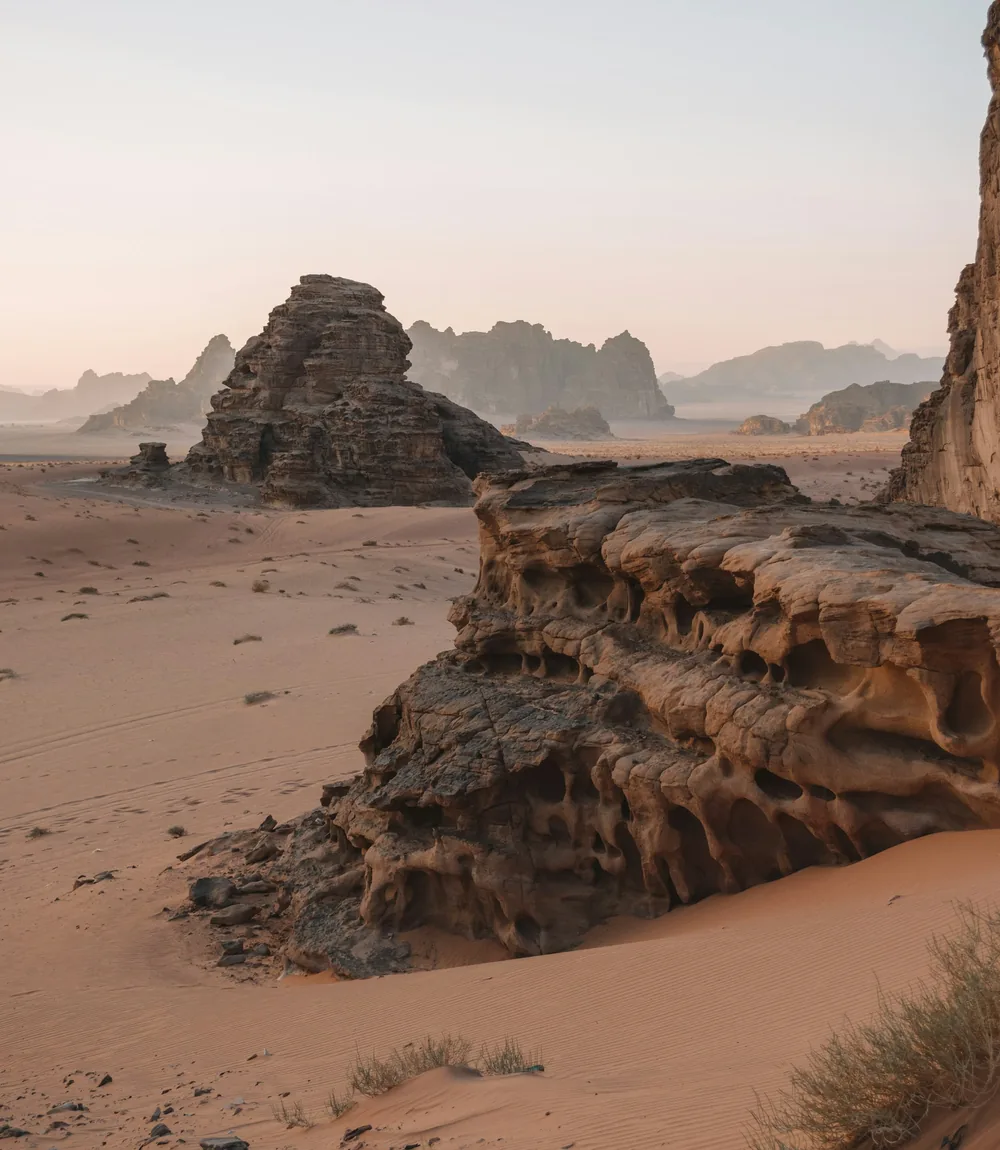 Czerwone wydmy u stóp potężnych klifów z piaskowca w Wadi Rum