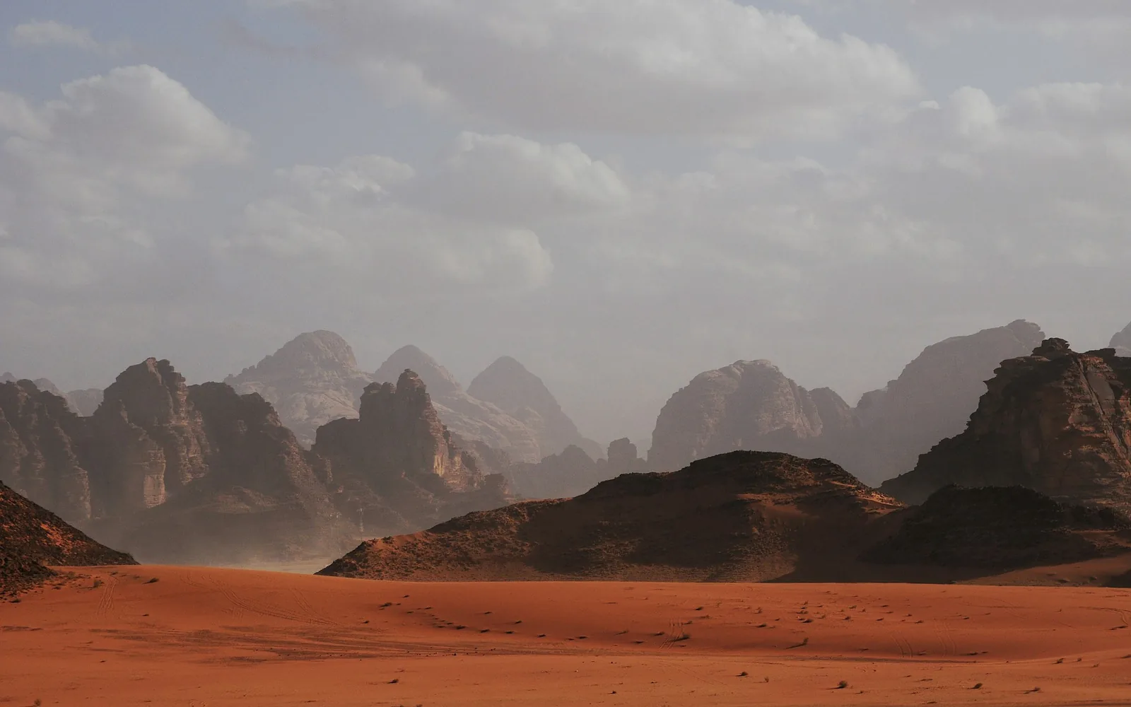 Wadi Rum çölünde, berrak bir gökyüzünün altında kızıl kum tepeleri ve yükselen kumtaşı kayalıkları.